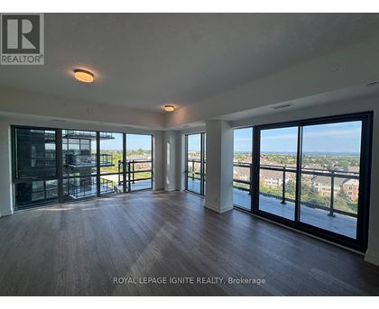 A spacious room with wooden floors and large windows overlooking a cityscape.
