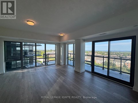 A spacious room with wooden floors and large windows overlooking a cityscape.