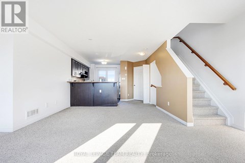 A spacious room with a staircase leading to the upper floor.