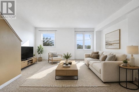 A well-lit living room with a beige sofa, a wooden coffee table, and a flat-screen TV.