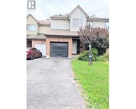 A red car is parked in front of a house with a garage.