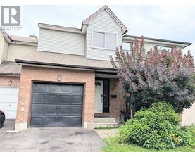 A house with a garage door and a tree in front.