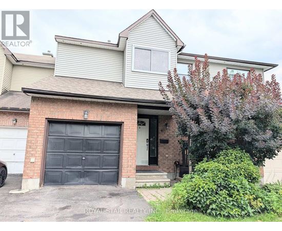 A house with a garage door and a tree in front.