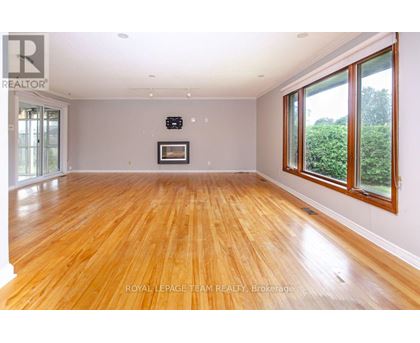 A spacious room with wooden flooring and a large window on the right side.