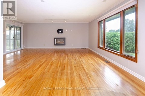 A spacious room with wooden flooring and a large window on the right side.