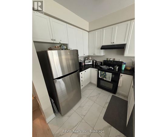 A kitchen with white cabinets and a stainless steel refrigerator.