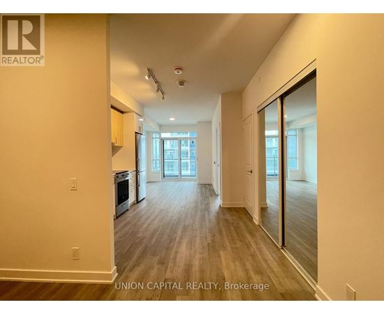 A spacious room with wooden flooring and a large window.