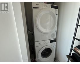A stack of white front loading washing machines in a small space.