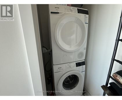 A stack of white front loading washing machines in a small space.