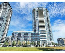 A large building with a glass facade stands in front of a blue sky.