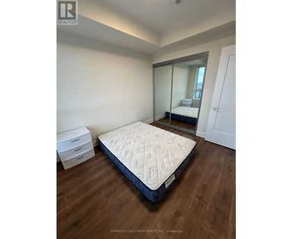 A bedroom with a large bed and a mirrored closet door.