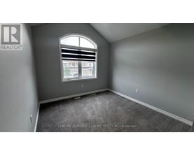 A room with a window showing a view of a building and trees outside.
