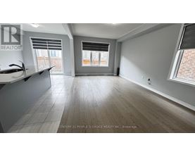 A spacious room with wooden flooring and a large window.