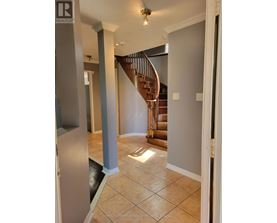 A spacious foyer with a staircase and a refrigerator.