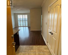 A room with wooden floors and white walls, with a door on the right side.