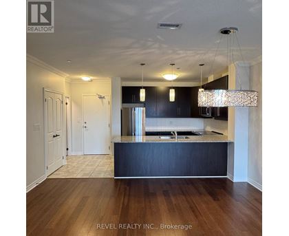 A kitchen with dark wood cabinets and a light wood floor.