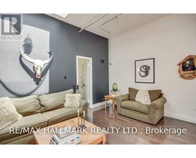 A living room with a couch, a chair, and a deer skull on the wall.