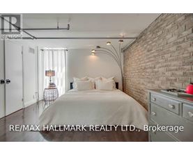A bedroom with a brick wall and a bed with white bedding.