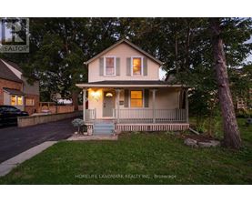 A house with a porch and a tree in front of it.