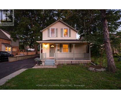 A house with a porch and a tree in front of it.