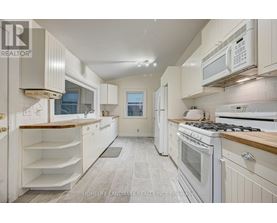 A white kitchen with a stove top oven and microwave.