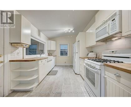 A white kitchen with a stove top oven and microwave.