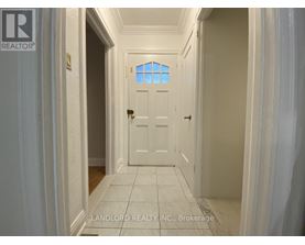 A hallway with a white door and a window above it.