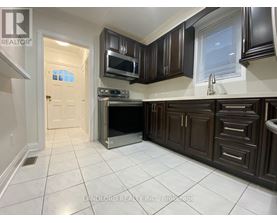 A kitchen with brown cabinets and a white tile floor.