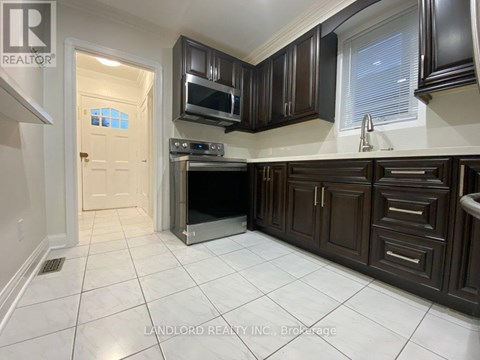 A kitchen with brown cabinets and a white tile floor.