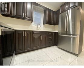 A kitchen with dark brown cabinets and a stainless steel refrigerator.