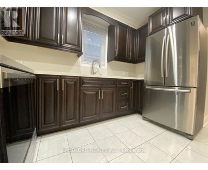 A kitchen with dark brown cabinets and a stainless steel refrigerator.