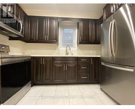 A kitchen with brown cabinets and a stainless steel refrigerator.