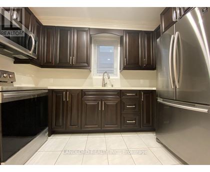 A kitchen with brown cabinets and a stainless steel refrigerator.
