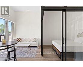 A bedroom with a bed, a couch, and a table with chairs is shown.