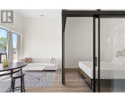 A bedroom with a bed, a couch, and a table with chairs is shown.