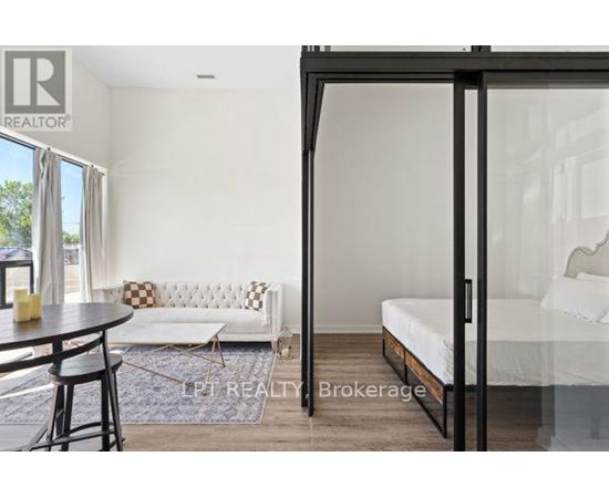 A bedroom with a bed, a couch, and a table with chairs is shown.