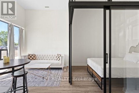 A bedroom with a bed, a couch, and a table with chairs is shown.
