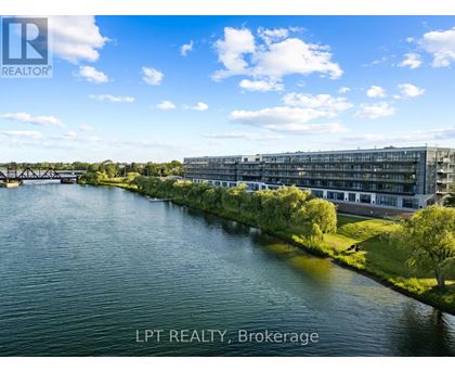 A river flows through a city with a bridge in the background and a building with the sign LPT REALTY, Brokerage.