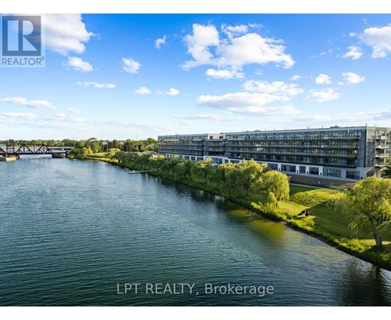 A river flows through a city with a bridge in the background and a building with the sign LPT REALTY, Brokerage.