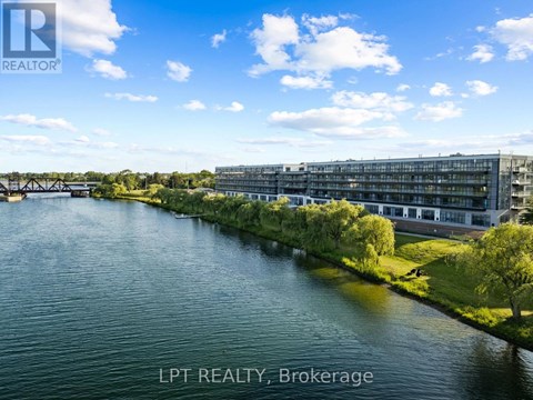 A river flows through a city with a bridge in the background and a building with the sign LPT REALTY, Brokerage.