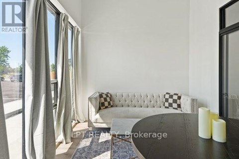 A living room with a white sofa and a black and white checkered pillow.