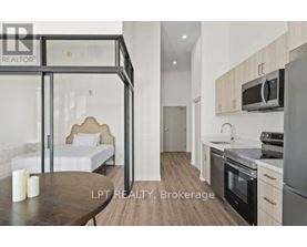 A modern kitchen with a dining table and a bed in the background.