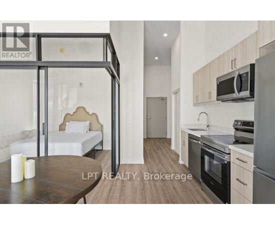 A modern kitchen with a dining table and a bed in the background.