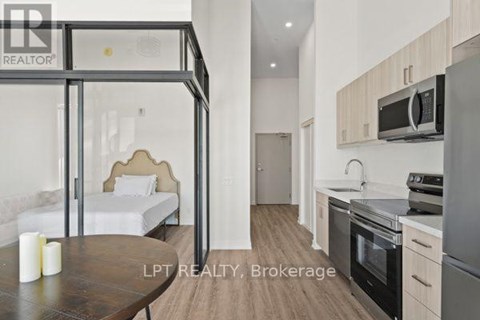 A modern kitchen with a dining table and a bed in the background.