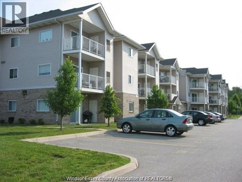 A car is parked in a parking lot in front of apartment buildings.