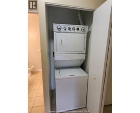 A white dryer and washer are stacked on top of each other in a small space.