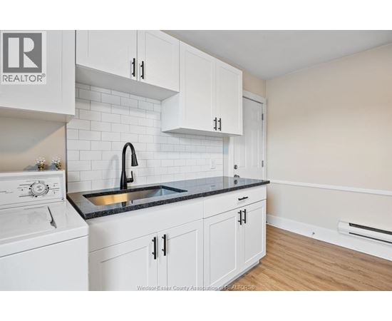 A kitchen with white cabinets and a black countertop.