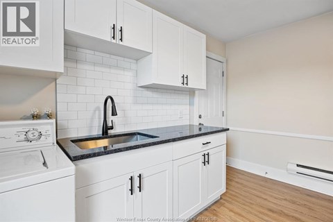 A kitchen with white cabinets and a black countertop.
