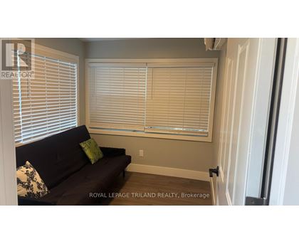 A living room with a couch and a window with blinds.