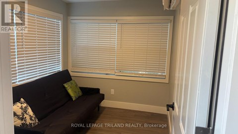 A living room with a couch and a window with blinds.